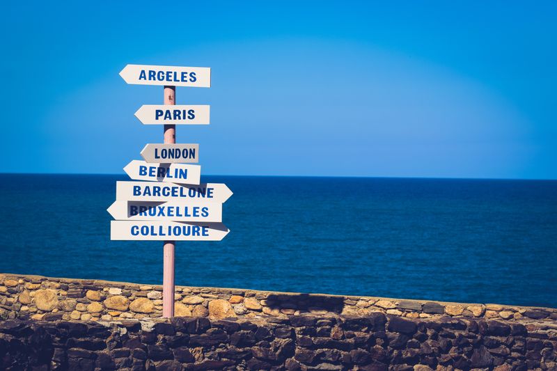 Arrow sings on a beach pointing to different international cities.