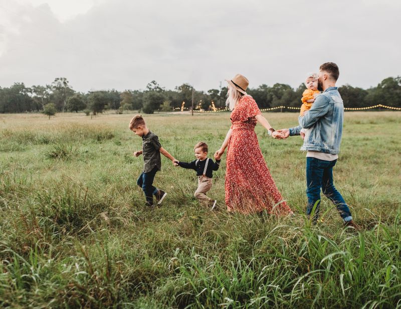 A family holding hands in a field at a festival.