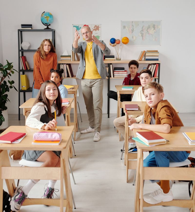 A teacher interacting with diverse group of students in modern classroom setting.