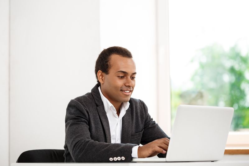 Image of a young man in a formal suit looking at a laptop.