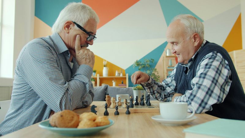 Two men playing chess and having coffee.