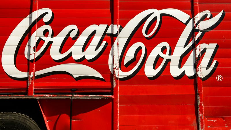 A Coca Cola advertisement on a delivery truck using a script font.