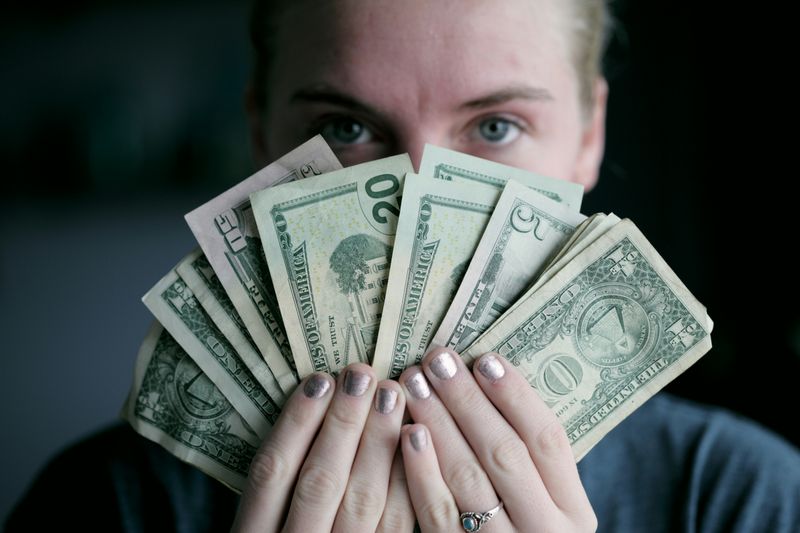 A person holding a pile of bills in front of their face.