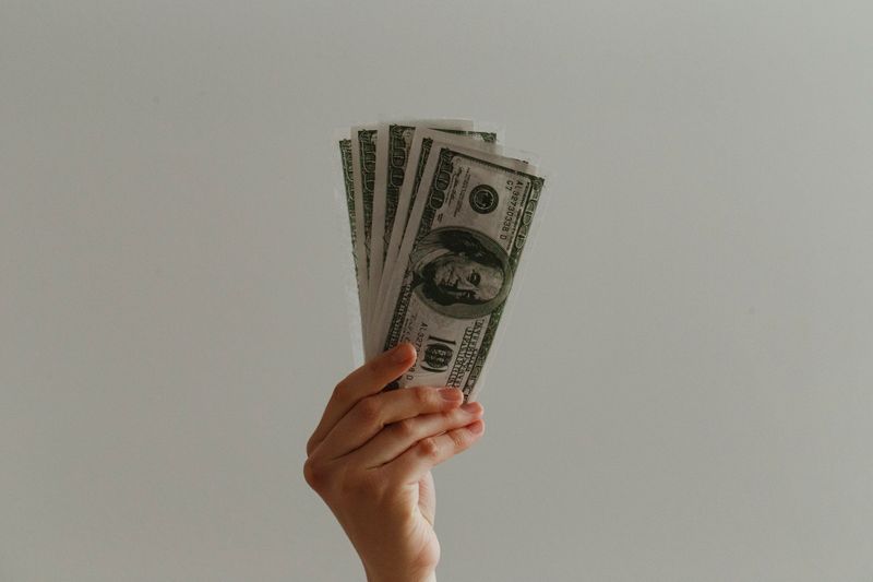 A hand holding hundred dollar bills.