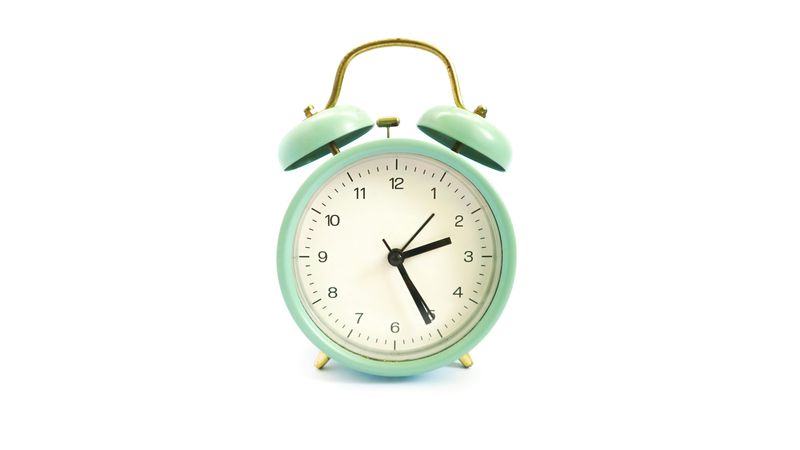 A vintage mint green alarm clock on a white background.
