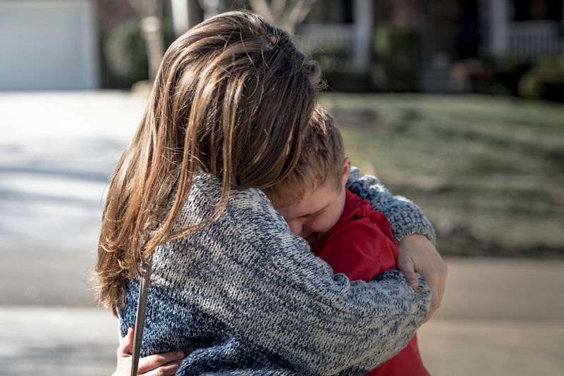 A mother and son hug each other.