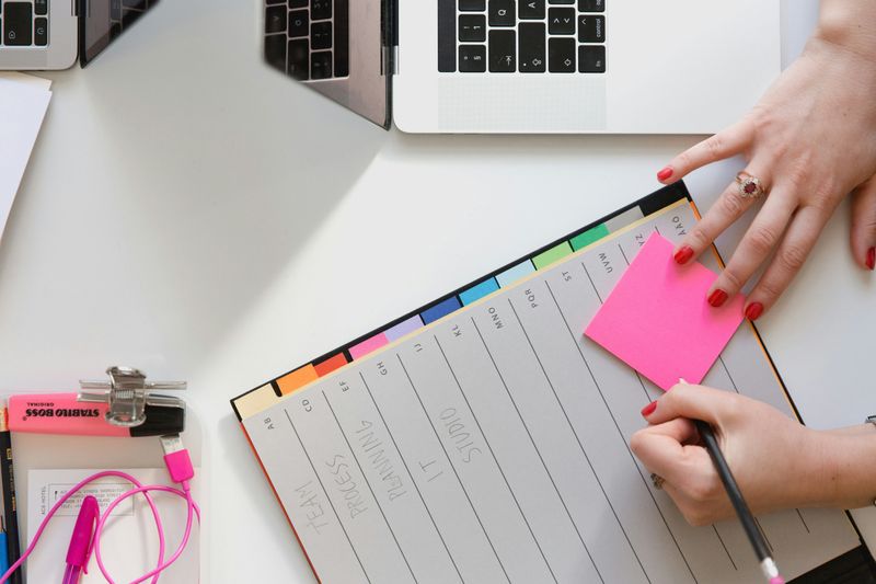 A teacher at a desk writing in their daily planner.
