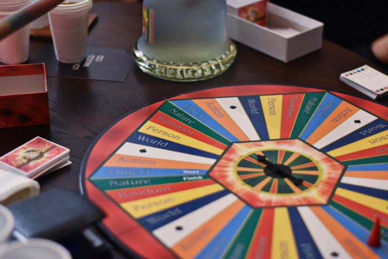A colored board with a spinning wheel for a word game. Each segment of the wheel has a different word and color.