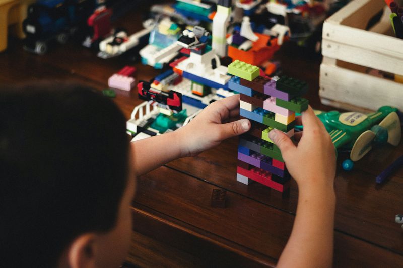 A child building a tower with Lego blocks.