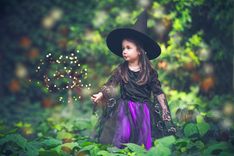 A young dressed as a wizard in a forest.