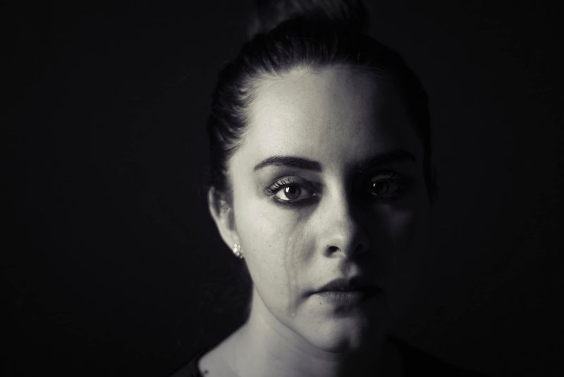 Woman with tear streaks down her right cheek.