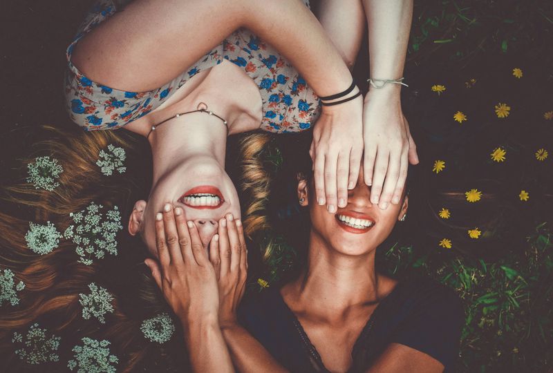 Two partners are smiling while covering each other's eyes with their hands, indicating affection and playfulness.