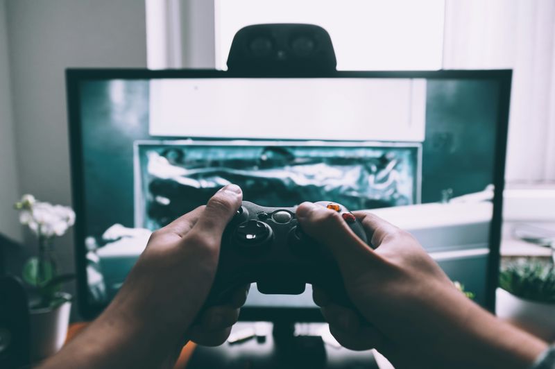 A man holding a gaming controller in front of a TV.