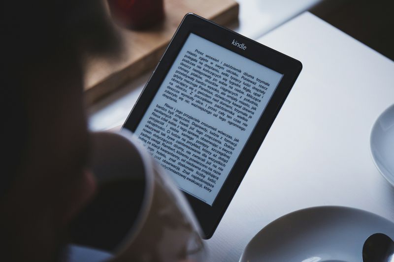 A person reading on a Kindle e-reader.