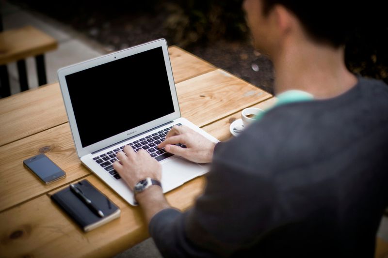 A man typing while sitting up straight in front of his laptop.