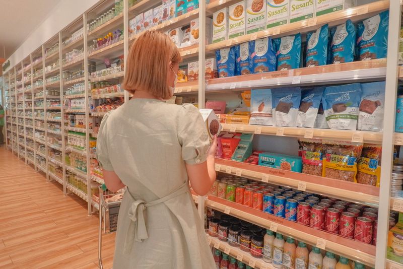 A woman choosing a product from grocery shelves.