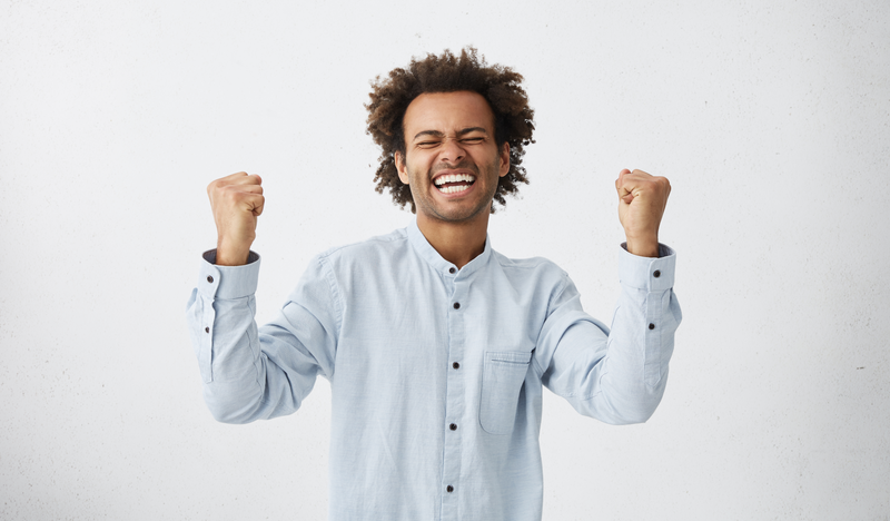 A young businessman putting fists in the air as a display of energy and confidence