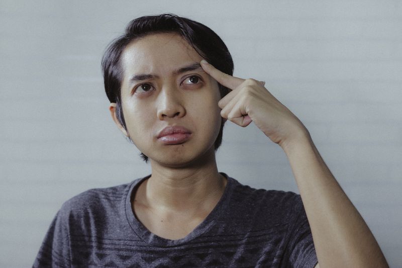 A young student pointing to his head.