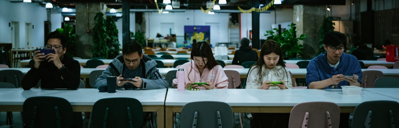 Five people all looking down at their cell phones.