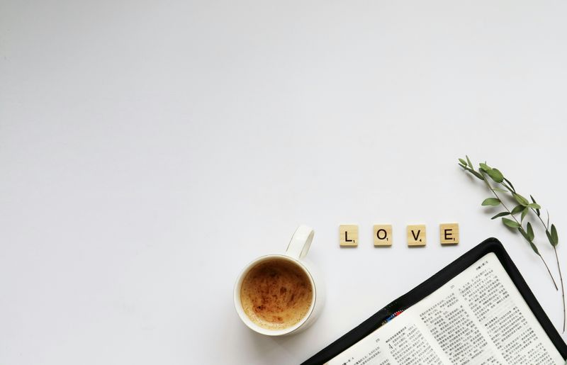 A coffee cup sitting next to a book, with the scrabble letters