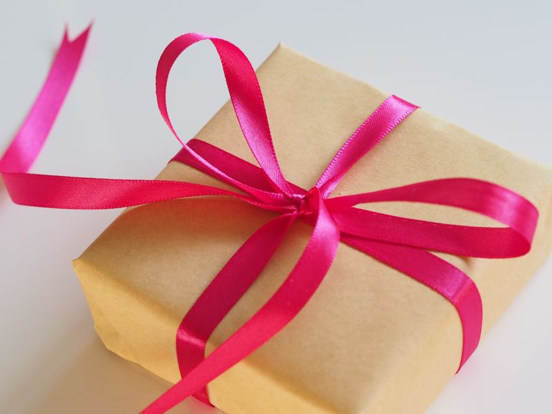 A brown package wrapped in a pink bow. 