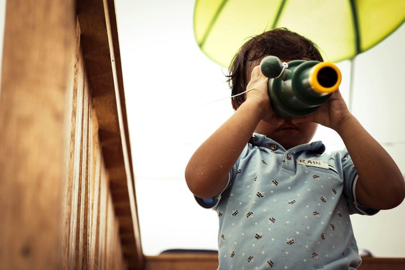 A child on a playground looking through telescope.