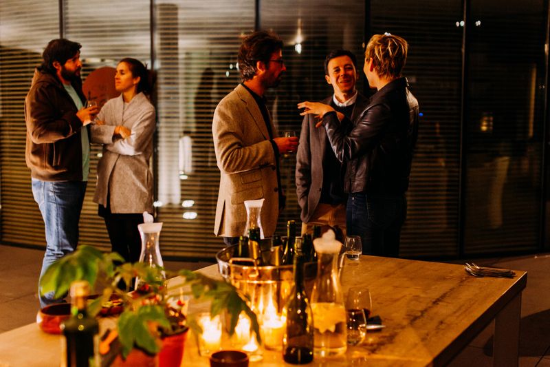 A dinner party with people talking in groups of two and three.