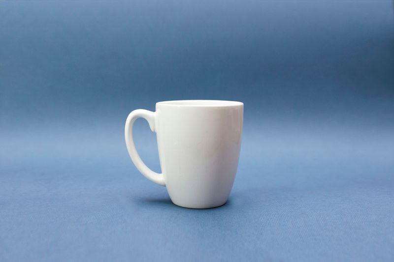 A white mug on a blue table.