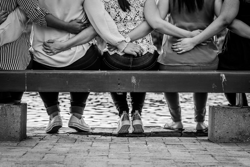 People sitting on a bench with arms around each other.