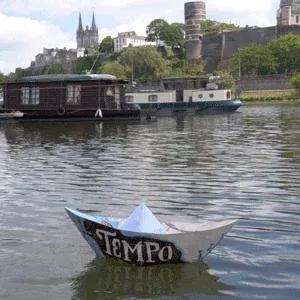 A paper boat floating on a river with a castle in background.