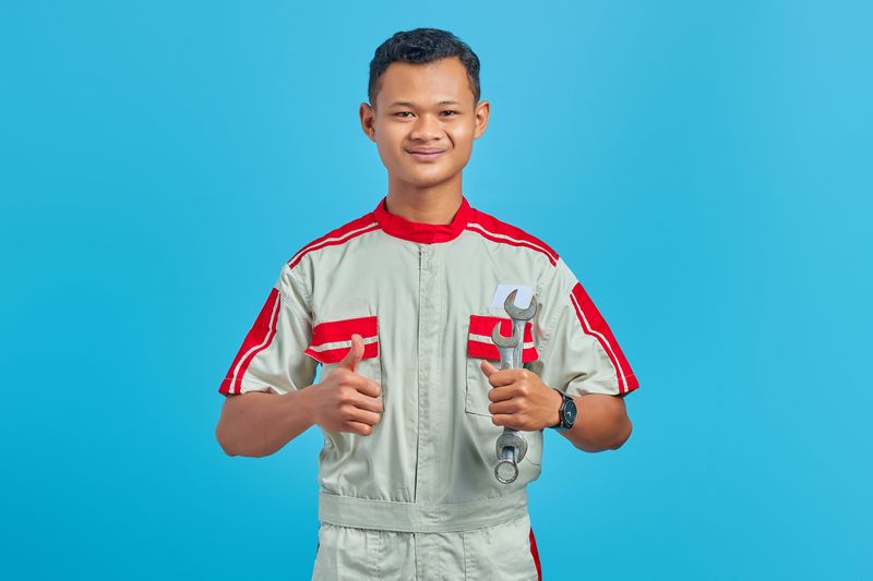 person smiling with a thumbs up and holding tools