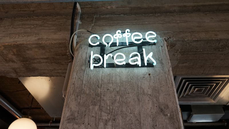 A neon sign in a coffee shop that reads, 
