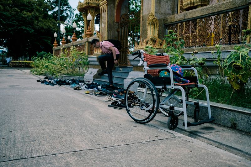 A man walks down steps littered by shoes, with a wheelchair waiting on the side.