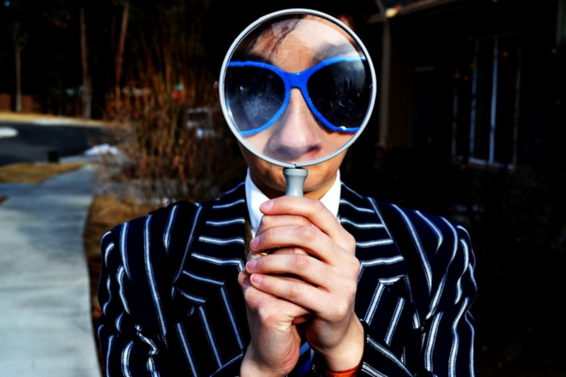 A man with a large magnifying glass in front of his face.