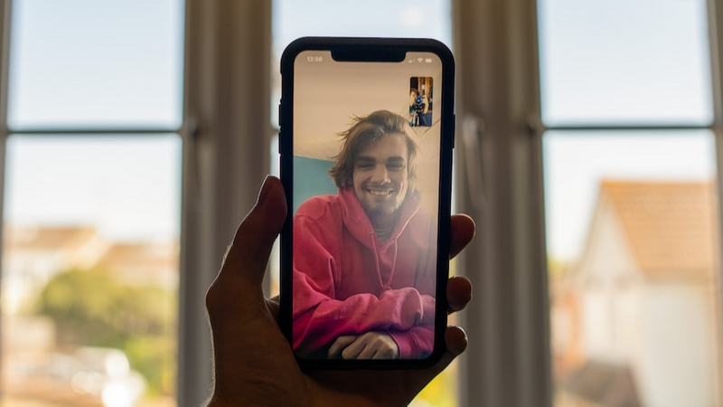 Hand holding a phone with a person on the screen.