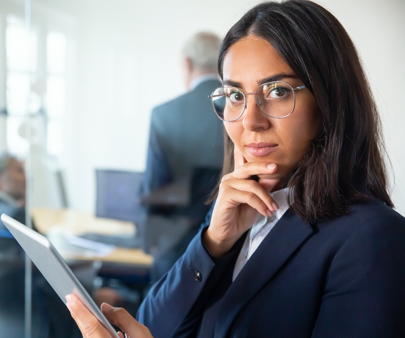 Confident business women in a suit holding a tablet and touching her chin.