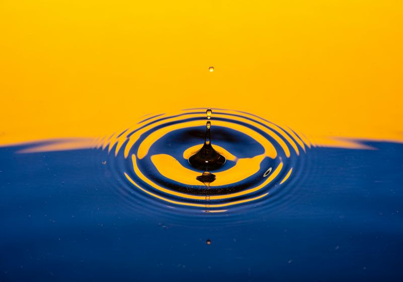 Yellow and Blue image of water drop creating ripple effect in water