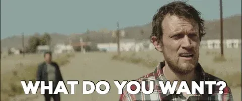 A man on a street raising his arms out wide and yelling, "What do you want?"