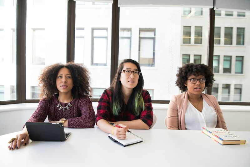 Three woman workers in an office unsure of how to respond