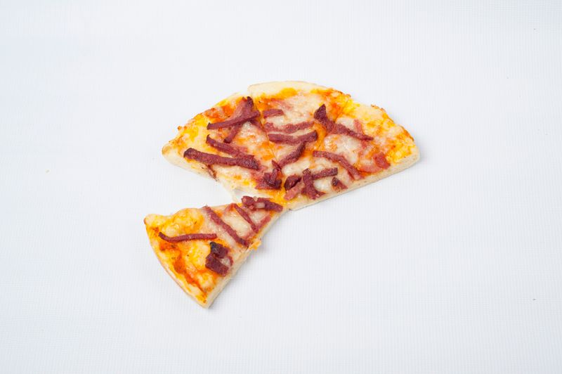 A small portion of a pizza with toppings, showing one slice slightly separated from the rest.