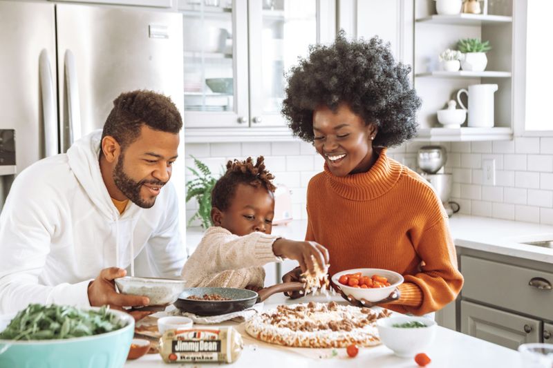 A Black family cooking pizza together.