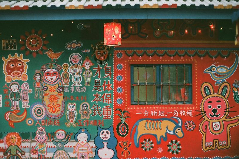 A colorfully painted house wall with Chinese characters and figures.