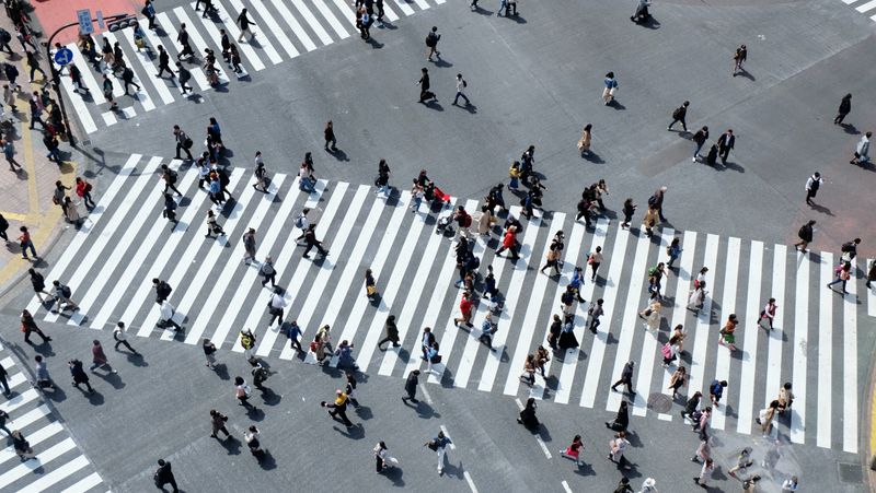 Aerial view of lots of people walking on a zebra crosswalk