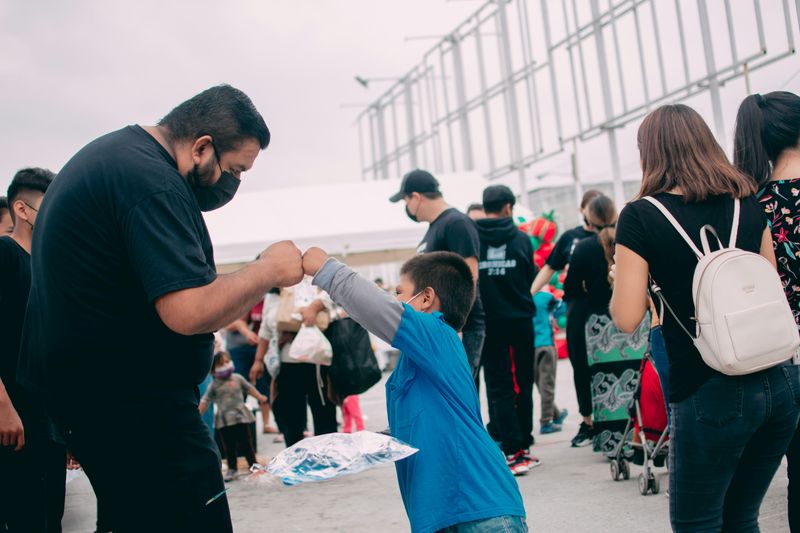 A man fist-bumping a boy at a charity event.