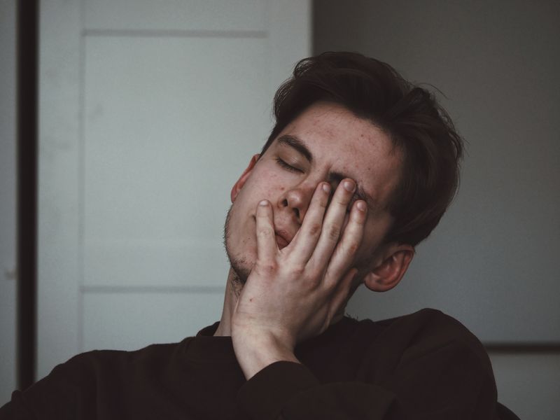 A man holding a hand to his face, looking exhausted.