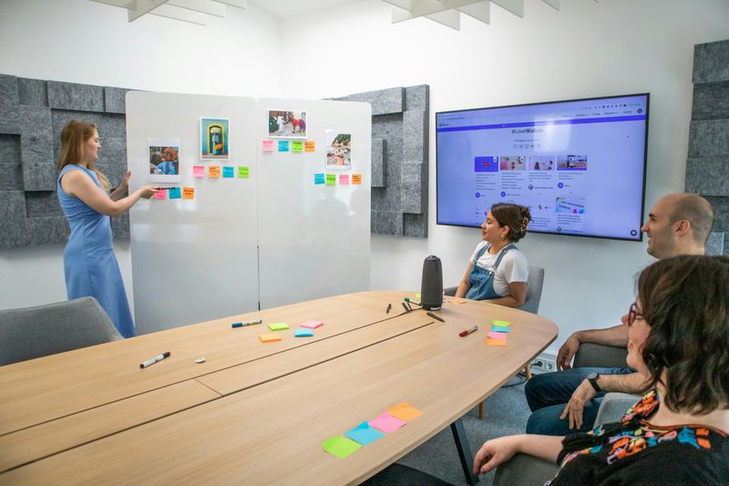 people in a meeting room looking at a white board with images and stickies
