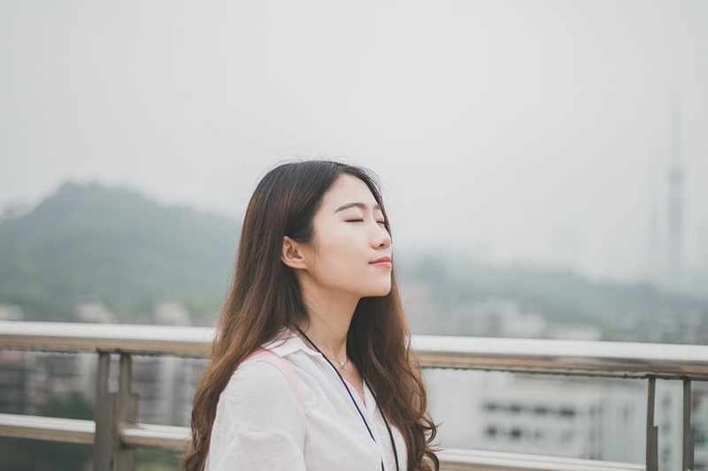 A woman on a bridge breathing deeply.