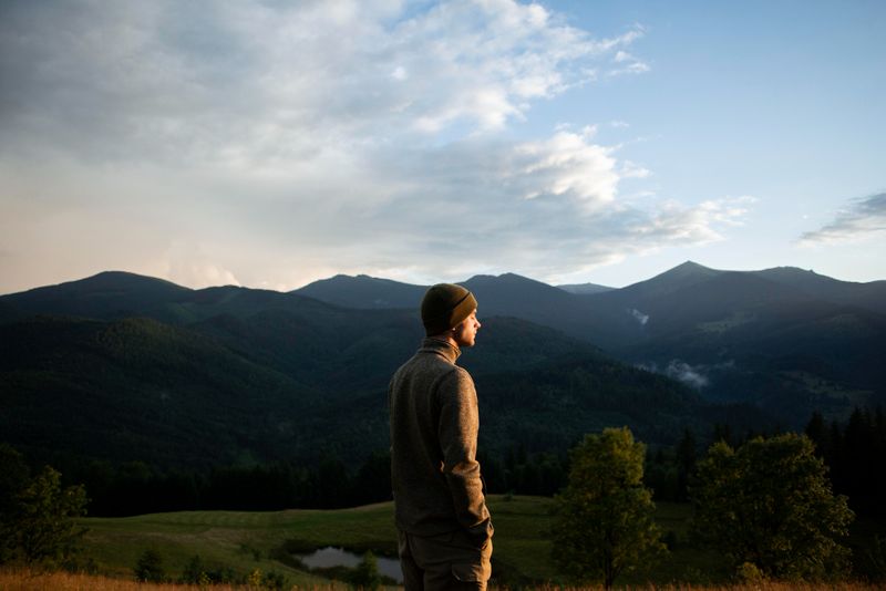 An image of a person with a mountain range in the background.