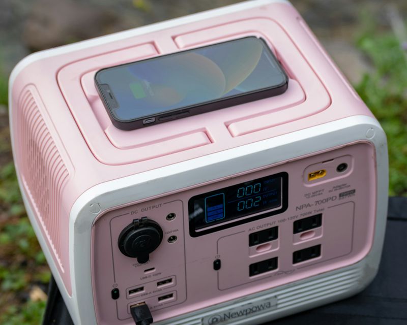 A phone is charging on a pink portable power station.