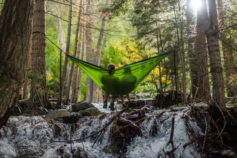 Two people sharing a hammock suspended over a river